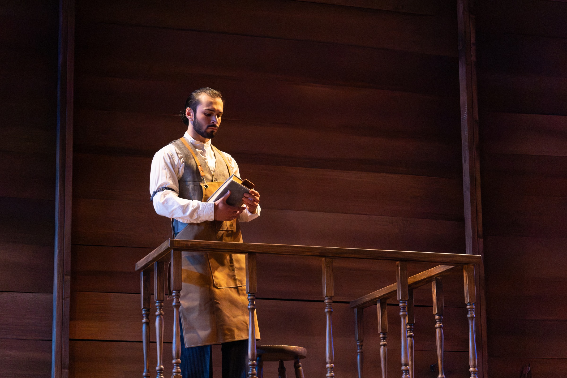 Kiran Behr as Palomo in Anna in the Tropics, holding a book onstage